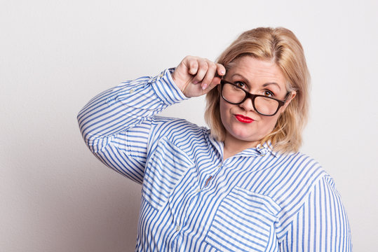 Portrait of an attractive overweight woman with glasses in studio.