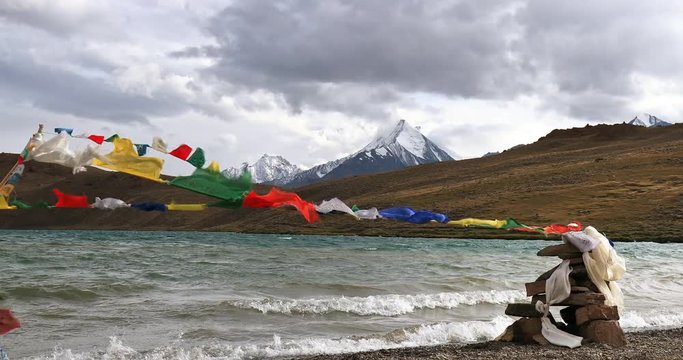 Buddhist prayer flags move by wind on bank of sacred Chandra Taal lake in Himalaya mountains, Spiti valley, north India