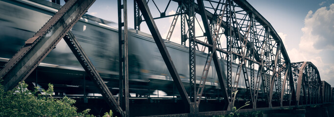 Old rusty truss bridge with moving freight train over the Red River on the border of Texas and Oklahoma