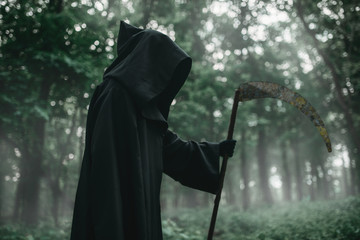 Death in a black hoodie with a scythe in forest