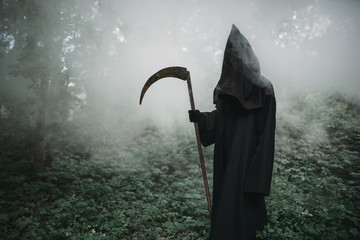 Death with scythe in dark misty forest