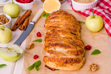 Apple pie with dried cherries, walnuts, lemon zest and cinnamon on white wooden background
