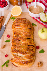 Apple pie with dried cherries, walnuts, lemon zest and cinnamon on white wooden background