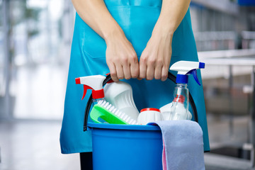 Cleaner with a bucket and cleaning products in an apron stands .