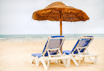 Focus on parasol. Sunbeds on snow-white sand