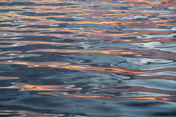 Natural background of blue-orange lake water with waves.