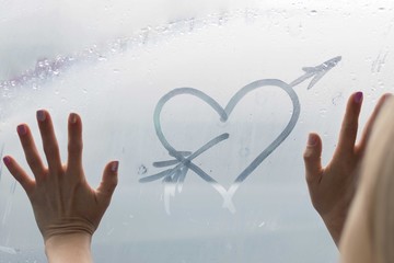 Heart on the fogged glass. A female hand drew a heart.