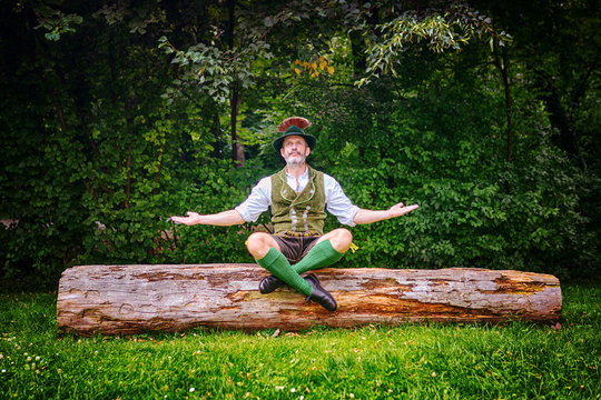 bavarian man sitting on tree stump and meditating