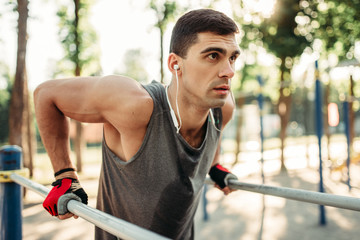 Male athlete exercises on parallel bars outdoor
