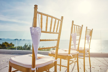 Close-up the gold chiavari chairs for beach wedding venue with cone of rose petal hanging
