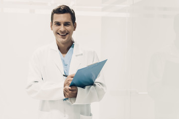 Smiling Young Doctor in White Uniform with Tablet.