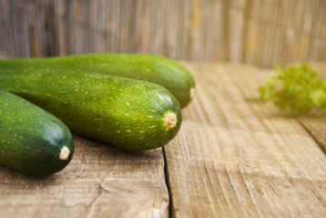 Fresh organic zucchini isolated on rustic wooden background. Summer vegetables, space for text.