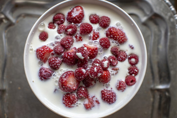 Raspberry with milk in a white bowl