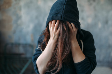 Female in a hoodie holds her head