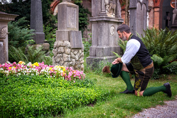 bavarian man kneeling in front of grave