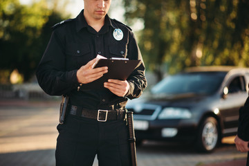 Cop with notebook in hands check the car