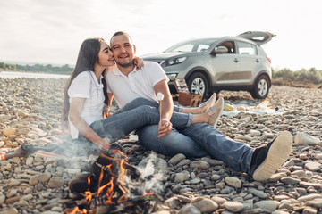Happy Traveler Couple on Picnic into the Sunset with SUV Car