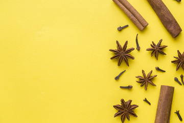 composition of star anise, cinnamon sticks and cloves on a yellow background. Abstract flat...