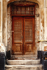 Fototapeta na wymiar old wooden door front on stone wall in the european city