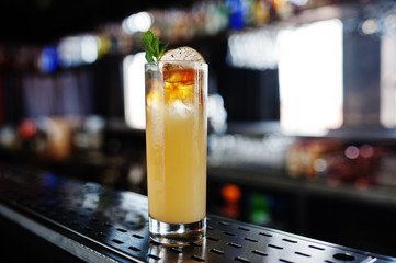 Alcoholic long yellow cocktail  in glass at bar table.