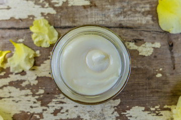 Close-up of an open box with face cream on a old rustic table, with roses leaves on the top. Shallow depth of focus, copy space. Spa, relax and beauty.