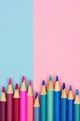 Pink and blue colored pencils against a pastel paper background. Bottom border, modern, minimal concept with copy space.