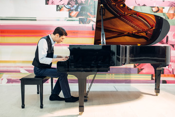 Male pianist practicing composition on grand piano