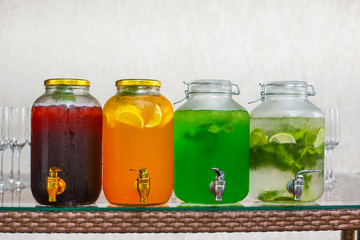 four glass jars with different lemonade mojito, tarragon, cherry, orange
