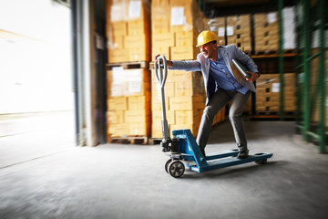 Customs manager drives forklift in the warehouse.Positive and fun business concept.