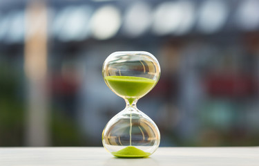 Close-up, hourglass with green sand on a blurred background