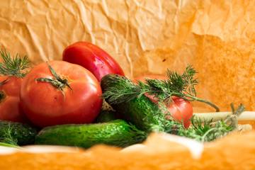 Arrangement  on the wrapping paper of a assortment of fresh vegetables, red pepper, garlic, green onions, tomatoes, cucumbers