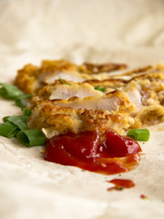 Fresh fried pork chops sprinkled with green onions and ketchup.  Arrangement  on the wrapping paper