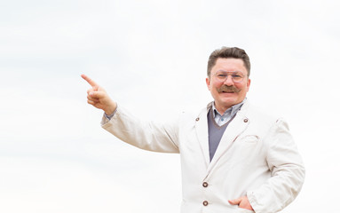 Pensioner. Adult middle-aged man with glasses and a mustache. Cheerful retired man points a finger up.