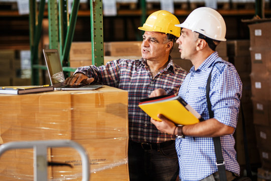 Male manager and warehouse worker checking list and inventory on laptop.Customs.
