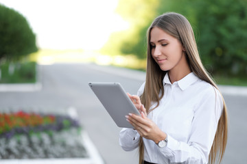 Young beautiful businesswoman student businesswoman uses tablet outdoor