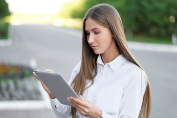 Young beautiful businesswoman student businesswoman uses tablet outdoor