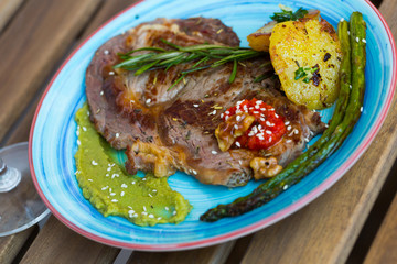 Fried beef loin with avocado puree and vegetables on wooden background