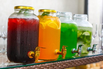 four glass jars with different lemonade mojito, tarragon, cherry, orange side view