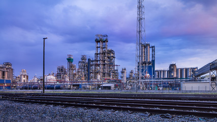 Fototapeta premium Petrochemical production plant against a cloudy blue sky at twilight, Port of Antwerp, Belgium.