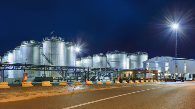 Massive tanks at illuminated petrochemical production plant at nighttime, Port of Antwerp, Belgium.