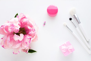 White background with copy space, pink peony flower, earrings, makeup brushes, small gift for girl, advertising space, top view