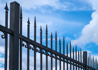 Beautiful decorative cast metal wrought fence against blue sky. Iron guardrail close up.