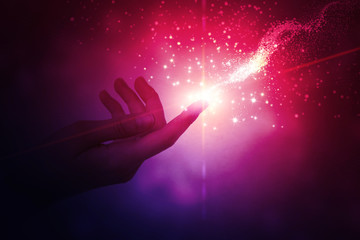 A female hand giving a stream of magical energy on a dark abstract background. The concept of magic...