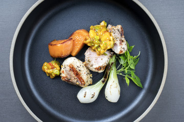 Modern barbecue crocodile tail eye fillet with roasted sweet potatoes and mango chili chutney as top view on a plate
