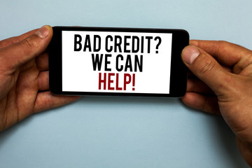 Word writing text Bad Credit question We Can Help. Business concept for Borrower with high risk Debts Financial Human hand hold smartphone with red and black letters on shadow blue floor.