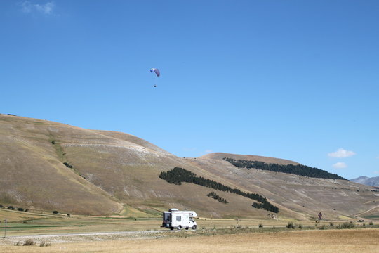 parapendio nel cielo blu con sullo sfondo la piccola italia