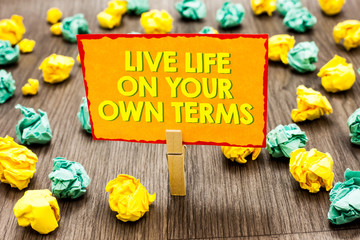 Handwriting text Live Life On Your Own Terms. Concept meaning Give yourself guidelines for a good living Paperclip hold written yellow page colorful paper lobs laid on wooden floor.