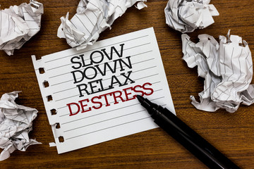 Text sign showing Slow Down Relax De Stress. Conceptual photo Have a break reduce stress levels rest calm Paper lumps laid randomly around white notepad touch black pen on woody floor.