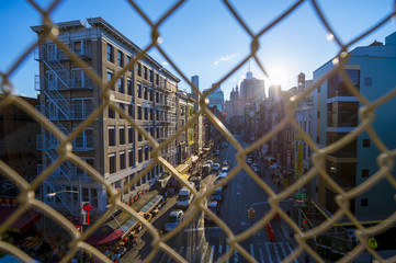 NEW YORK - CIRCA AUGUST, 2017: Downtown Manhattan and Chinatown viewed through a chainlink fence on the Manhattan Bridge. - obrazy, fototapety, plakaty