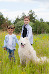boy and girl in the summer with a big mount dog of the Samoyed